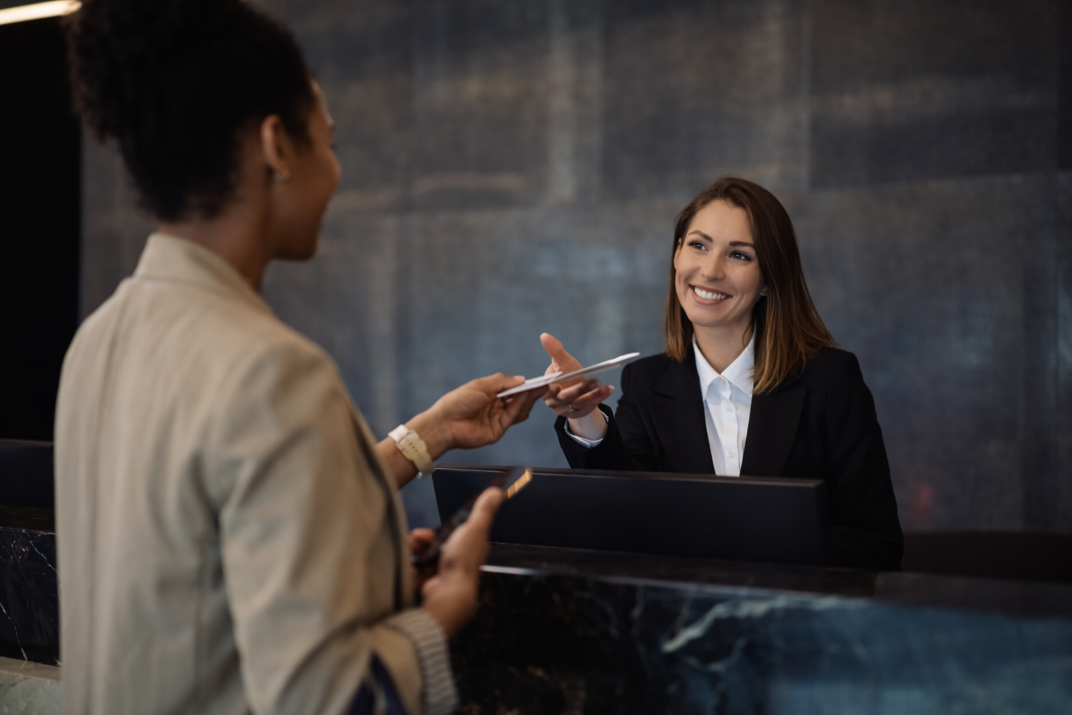 a young female hotel concierge checking a guest in