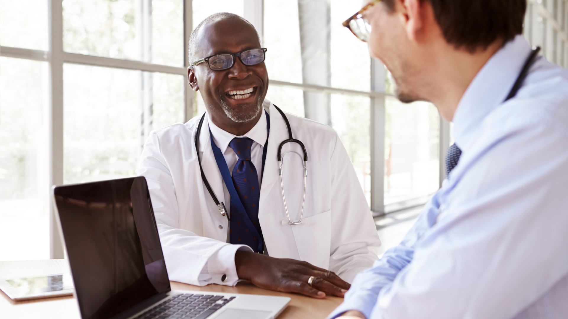 Doctors reviewing information on a laptop representing AI in healthcare operations.