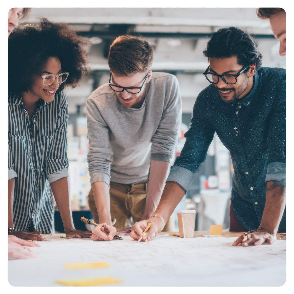 Team collaborating around a table reviewing plans and ideas during a workplace strategy session.