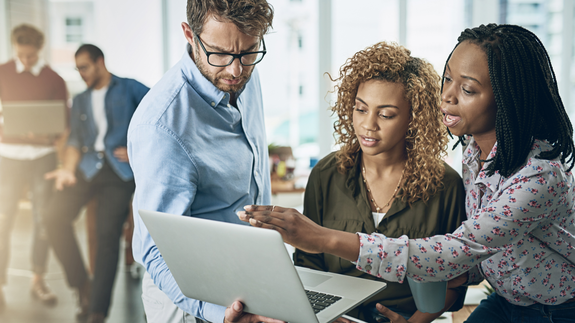 Featured image: Team collaborating around a laptop representing workforce adoption of new technologies.How workforce adoption unlocks technology ROI