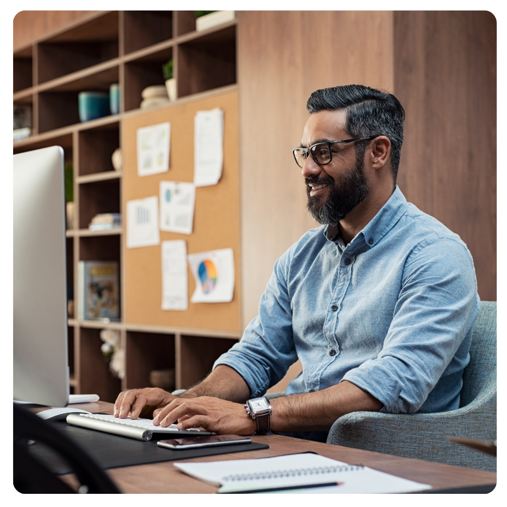 middle aged man in glasses typing at a desktop computer