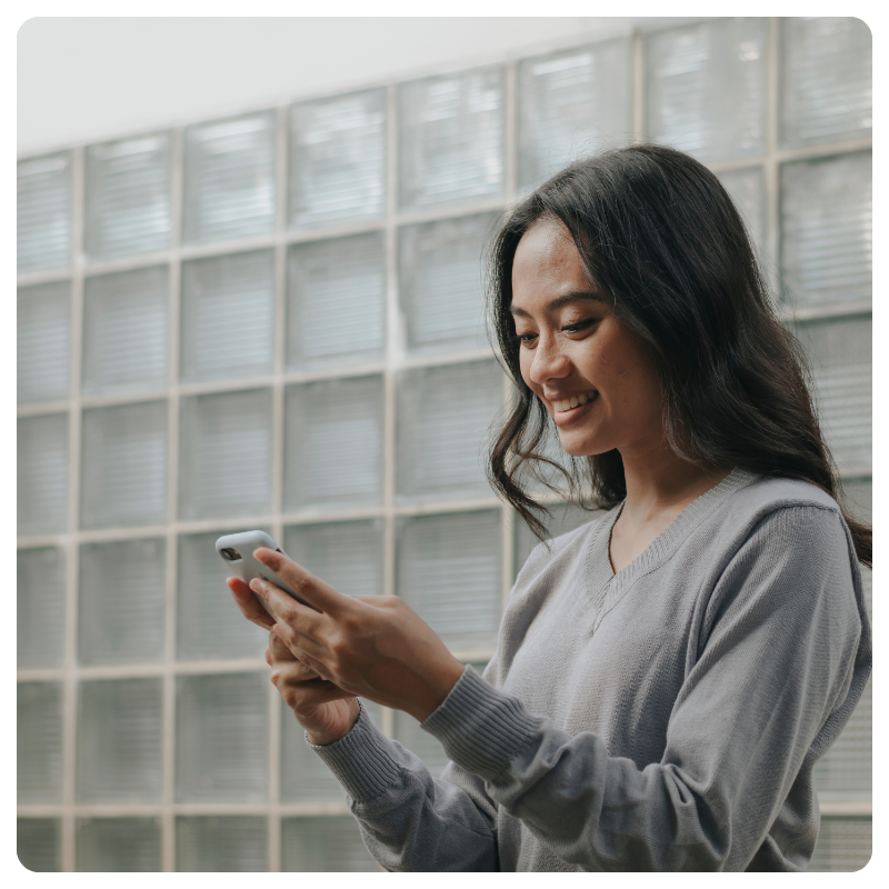 young female smiling while looking at smart phone